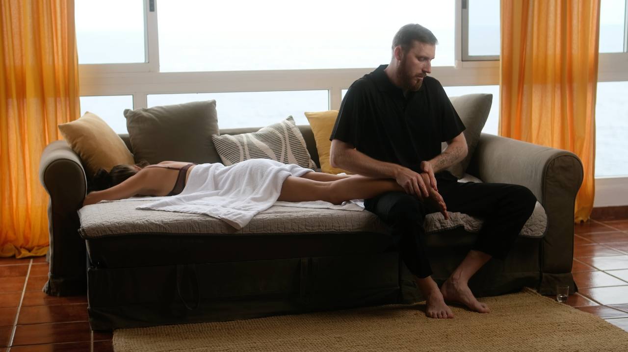 Deny giving a relaxing massage at home on a couch by the window